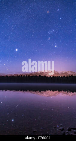 Orion e Canis Major oltre il Lago di Annette, nel Parco Nazionale di Jasper, con Sirius e altre stelle si riflette nelle acque. Orion app Foto Stock