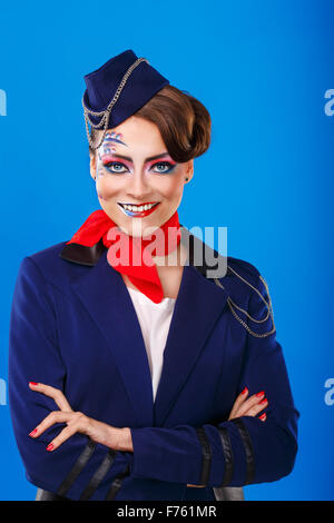 Hostess con faccia arte incontra i passeggeri. Giovane ragazza attraente in una tuta blu gli assistenti di volo si erge bracci ripiegati. Foto Stock