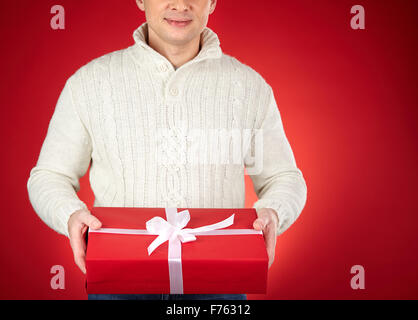 Giovane uomo in bianco maglione rosso mostra giftbox Foto Stock