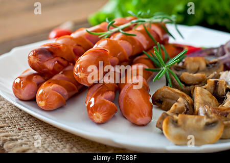 Salsicce fritte con le verdure su una piastra bianca Foto Stock