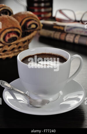 Tazza di caffè sul tavolo con panini e quotidiani Foto Stock