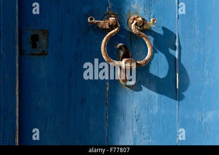 Porta vecchia respingente sul porta con uno sfondo blu. Uno strumento metallico ad una porta a battente e battuta dai visitatori per attirare atten Foto Stock