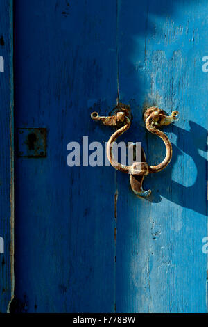 Porta vecchia respingente sul porta con uno sfondo blu. Uno strumento metallico ad una porta a battente e battuta dai visitatori per attirare atten Foto Stock