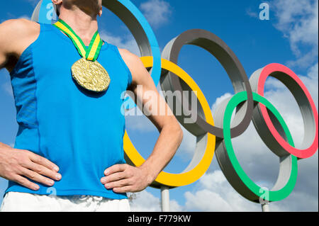 LONDON, Regno Unito - 14 ottobre 2015: Medaglia d'oro atleta sta in piedi di fronte ad anelli olimpici nel Queen Elizabeth Olympic Park. Foto Stock