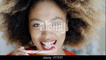 Giovane donna di mordere una festosa candy cane Foto Stock