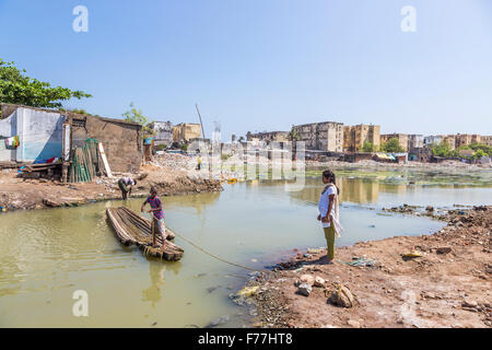 Legno di fortuna traghetto per attraversare un torrente azionato da un giovane ragazzo in baraccopoli sulla Ocean Shore a Chennai, Tamil Nadu, nell India meridionale Foto Stock