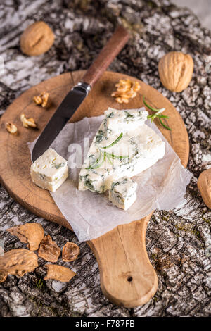Delizioso formaggio con stampo sul tagliere di legno Foto Stock