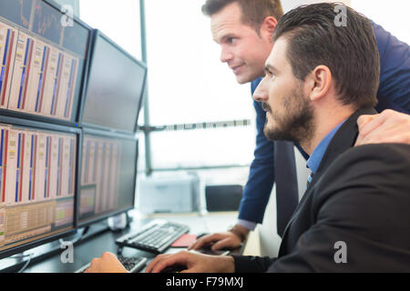 Stock traders looking at computer screens. Foto Stock