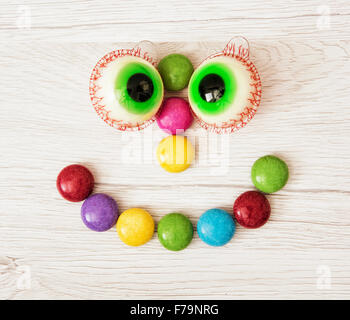 La faccina sorridente di smarties e gomme da masticare in forma di occhi. Funny pasticceria. Foto Stock