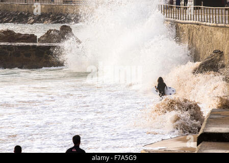 3 surfers camminando lungo il suono con le onde del mare, Cascais, Portogallo Foto Stock