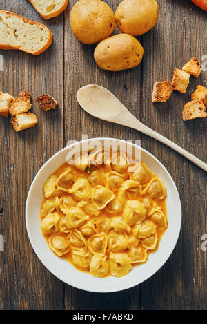 Zuppa di tortellini in piastra bianca sul tavolo di legno Foto Stock
