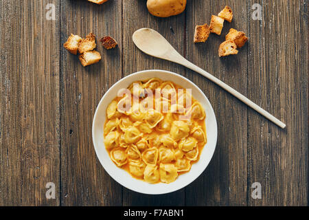 Zuppa di tortellini in piastra bianca sul tavolo di legno Foto Stock