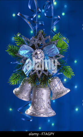 Festive Capodanno Natale ancora vita nei toni del blu con tre mani di argento campane che sono sospesi verso il basso da un abete. Foto Stock