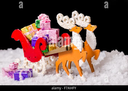 Ancora in vita di decorazione di natale renne e Santa sleigh con doni in snow è isolato su sfondo nero, primo piano Foto Stock