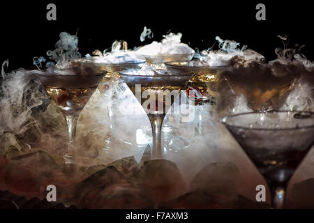 Martini drink con ghiaccio secco effetto fumo e splash, servito sul banco  bar con bottiglie di sfocatura sullo sfondo Foto stock - Alamy