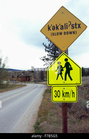 Cartello bilingue in Okanagan indiano e lingue inglese Oliver, British Columbia, Canada - Rallentare, persone / bambini Passeggiate Foto Stock