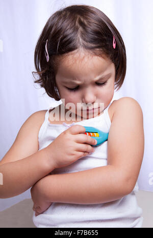 Carino bambina riproduzione medico con termometro giocattolo. Isolato su sfondo bianco Foto Stock