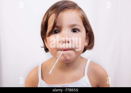 Bambina con un clinici di vetro a mercurio del tipo a termometro in bocca alla ricerca per la fotocamera Foto Stock