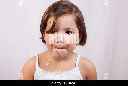 Bambina con un clinici di vetro a mercurio del tipo a termometro in bocca Foto Stock