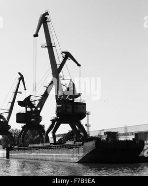 Sagome scure del porto industriale di gru, Fiume Danubio, Bulgaria. Foto in bianco e nero Foto Stock