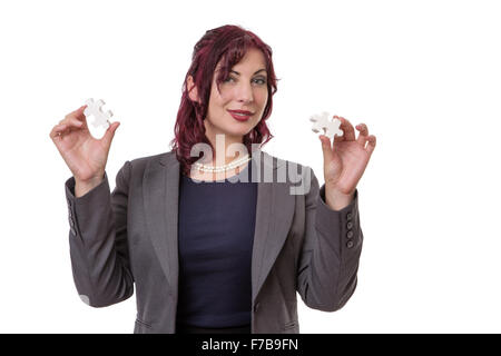 La donna in una tuta holding jigsaw/i pezzi del puzzle, uno in ogni mano Foto Stock