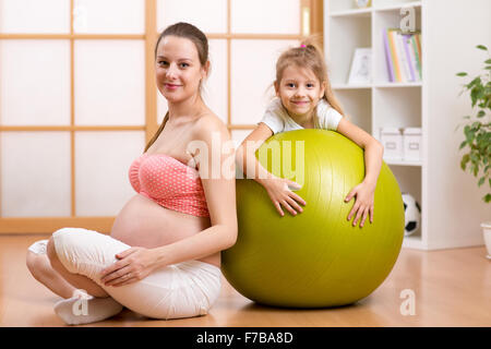 Famiglia, bambini, donne in stato di gravidanza, fitness. Uno stile di vita sano concetto - happy donna incinta esercitando con fitball a casa. Foto Stock
