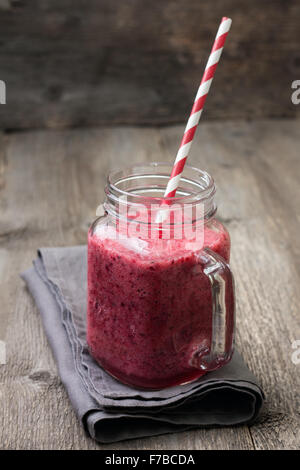 Berry smoothie di cowberry, mirtilli rossi in un bicchiere su un sfondo di legno Foto Stock