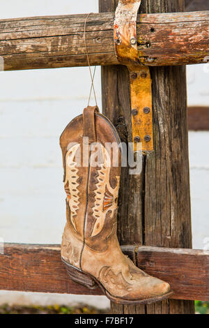 Il vecchio stivali da cowboy appesi al bar di fronte al maneggio Foto Stock