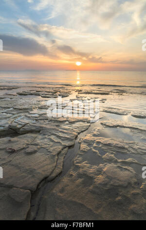 Rocce fuori luogo del Mare Ionio nello stretto di Corfu vicino a Kassiopi Corfù. Il sole tramonta sul mare. Foto Stock