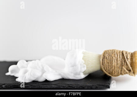 Pennelli per barba e schiuma su sfondo bianco Foto Stock