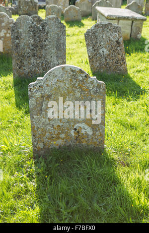 Vecchie lapidi in un cimitero essendo retroilluminati da sun. Foto Stock