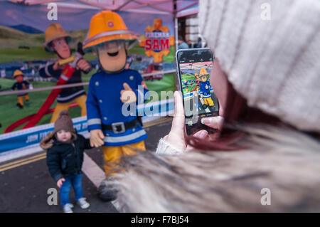 Londra, Regno Unito. Il 28 novembre 2015. Una donna prende una foto di 'Fireman Sam' come centinaia di persone si radunano in Regent Street, che è stata chiusa al traffico, per godere di personaggi giocattolo, giocattolo e le attività correlate. Hamley, il più antico negozio di giocattoli nel mondo, ospitati, ciò che era stato pubblicizzato come il più grande parata giocattolo mai visto in Gran Bretagna. Credito: Stephen Chung / Alamy Live News Foto Stock