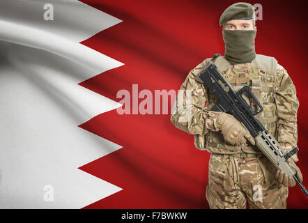 Soldier holding mitragliatrice con bandiera nazionale sullo sfondo - Bahrain Foto Stock