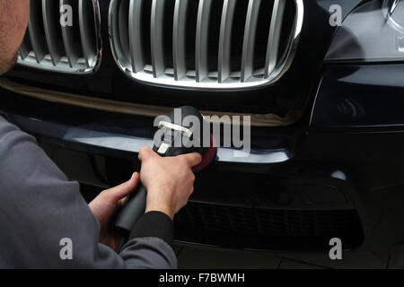 Il lavoratore lucidi un bumper car cruscotto con l'attrezzo elettrico. Close up Foto Stock