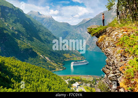 Tourist permanente sulla roccia, la nave di crociera nel Fiordo di Geiranger in background, Norvegia Foto Stock