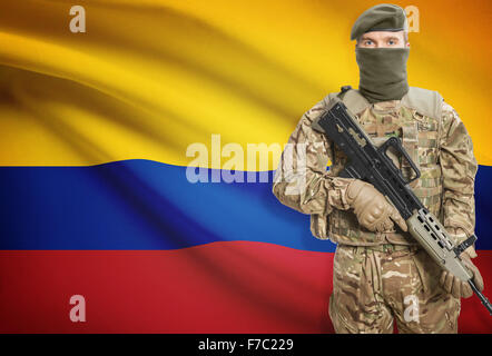 Soldier holding mitragliatrice con bandiera nazionale su sfondo - Colombia Foto Stock