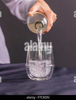 Primo piano sulla casalinga versare acqua in vetro dal filtro acqua brocca Foto Stock