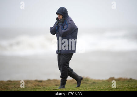 Un viandante è bruciato in presenza di venti forti durante la tempesta Clodagh a Porthcawl lungomare, nel Galles del Sud. Foto Stock