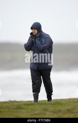 Un viandante è bruciato in presenza di venti forti durante la tempesta Clodagh a Porthcawl lungomare, nel Galles del Sud. Foto Stock