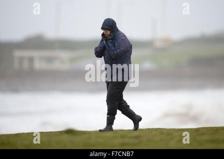 Un viandante è bruciato in presenza di venti forti durante la tempesta Clodagh a Porthcawl lungomare, nel Galles del Sud. Foto Stock