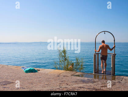 Trieste, Italia, uomo di prendere una doccia a Barcola promenade e libera la balneazione strand, popolare spot estivo della città Foto Stock
