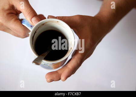 Una tazza di caffè nero al mattino in mani femminili. Tazza da sopra Foto Stock