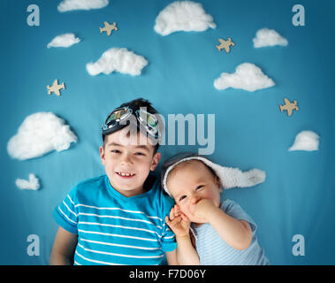 Due ragazzi che giace su una coperta con il bianco delle nuvole Foto Stock