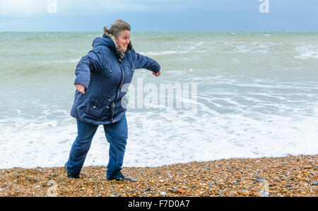 Donna di mezza età su una spiaggia in esecuzione dalle onde nel Regno Unito. Foto Stock