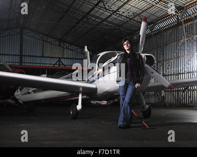 Bella giovane donna modello in moda in posa di fronte del vecchio aereo privato Foto Stock