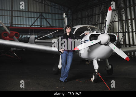 Bella giovane donna modello in moda in posa di fronte del vecchio aereo privato Foto Stock