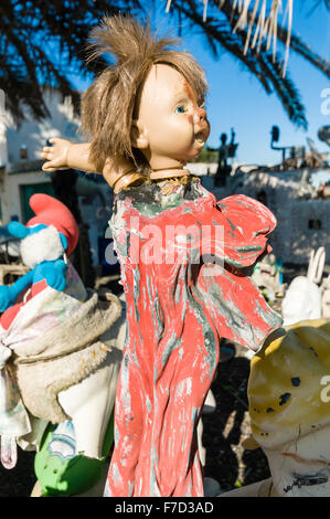 Creepy, paura di bambola sulla testa di una statua religiosa sul display sulla parete di un giardino Foto Stock