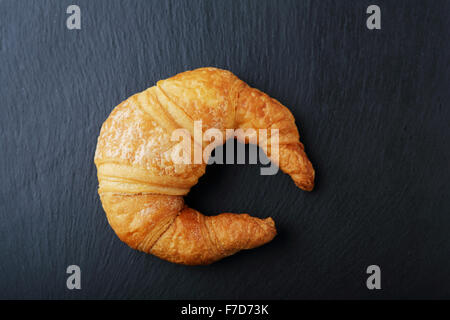 Freschi croissant d'oro su sfondo scuro, cibo vista superiore Foto Stock