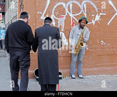 Due uomini ebrei, un cieco, ascoltare un americano africano musicista jazz giocando da solo su Bedford Avenue a Williamsburg, Brooklyn. Foto Stock