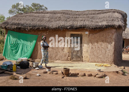 Donna di mais di essiccazione fuori la sua paglia casa di fango, Saakpuli village, nel nord del Ghana Foto Stock